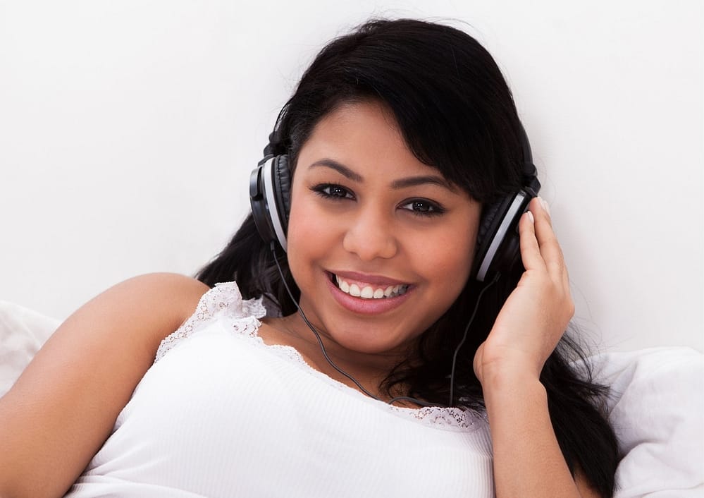 lady smiling while listening to music in bed